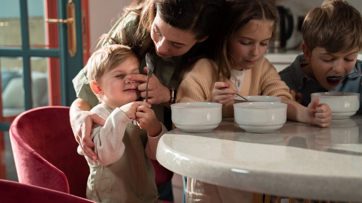 A loving mother with her children enjoying breakfast together in a sunlit kitchen.